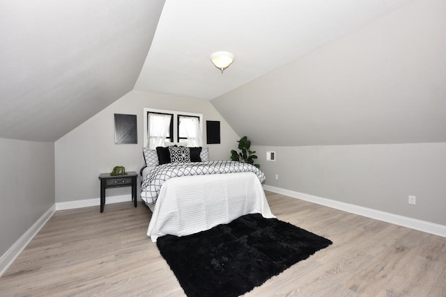 bedroom featuring lofted ceiling, light wood-style floors, and baseboards