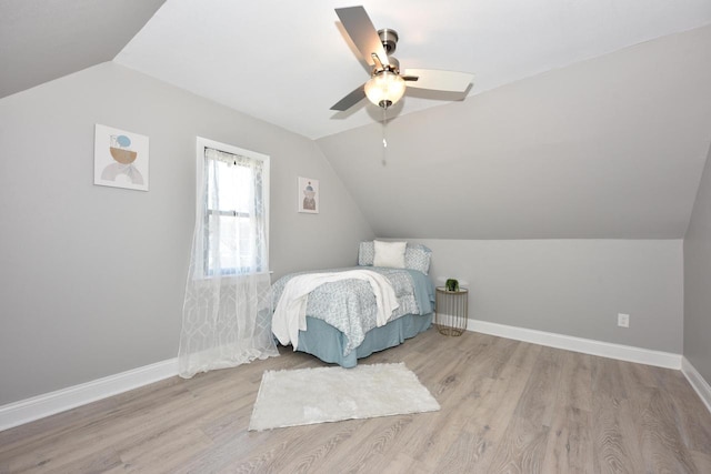 bedroom with a ceiling fan, vaulted ceiling, wood finished floors, and baseboards