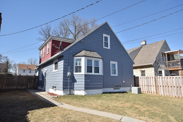 back of house featuring a yard, central AC unit, and fence