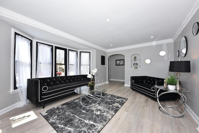 living area with crown molding, wood finished floors, baseboards, and arched walkways