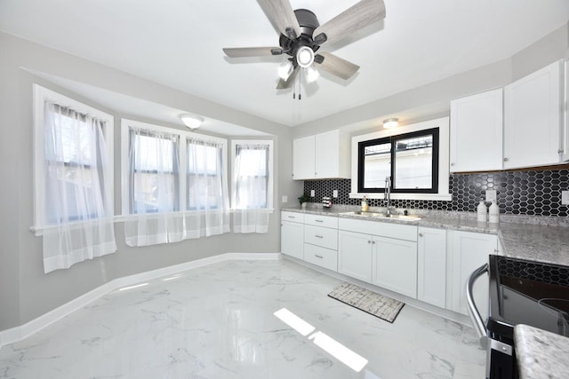 kitchen with tasteful backsplash, baseboards, electric range, marble finish floor, and a sink