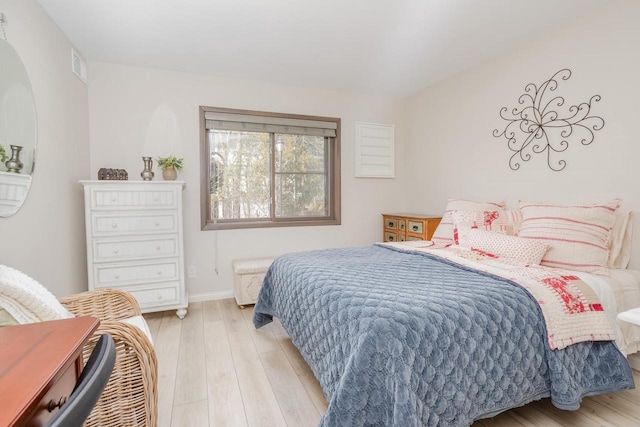 bedroom featuring light wood finished floors, visible vents, and baseboards