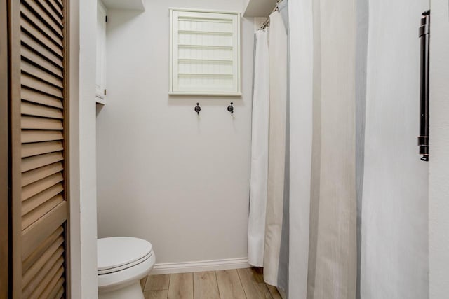 full bath with toilet, baseboards, and wood finished floors