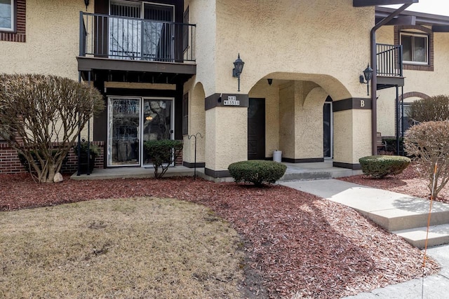 view of exterior entry featuring stucco siding and a balcony