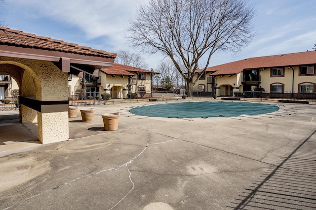 community pool featuring a patio, fence, and a residential view