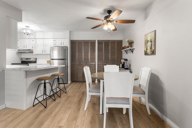 dining room featuring baseboards, a ceiling fan, and light wood finished floors