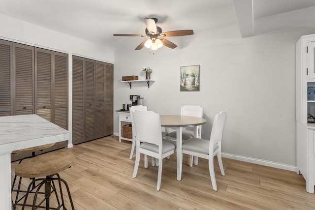 dining area featuring baseboards, beam ceiling, light wood-style flooring, and a ceiling fan