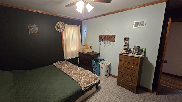 carpeted bedroom with visible vents, baseboards, ornamental molding, and a ceiling fan