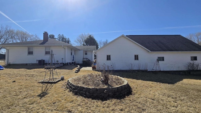 rear view of property featuring central AC unit, a lawn, and a chimney