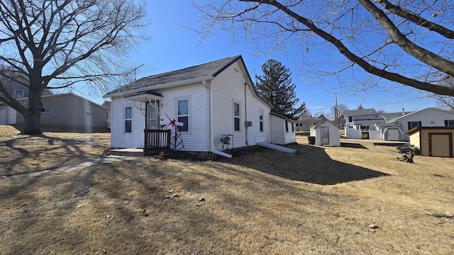 rear view of house featuring an outdoor structure, a residential view, and a shed