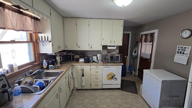 kitchen with stainless steel microwave, light countertops, white dishwasher, fridge, and a sink