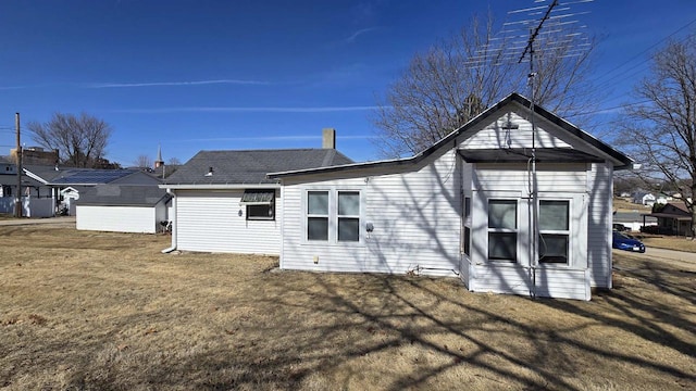 back of property with a lawn, an outdoor structure, and a storage shed