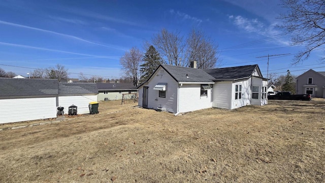 back of house with a shingled roof and a chimney