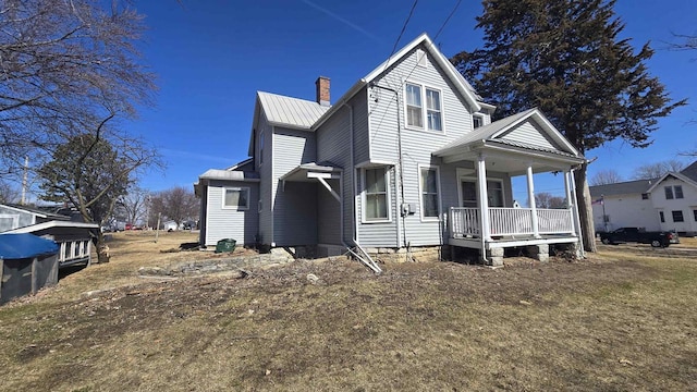 view of front of home with a chimney, covered porch, and metal roof