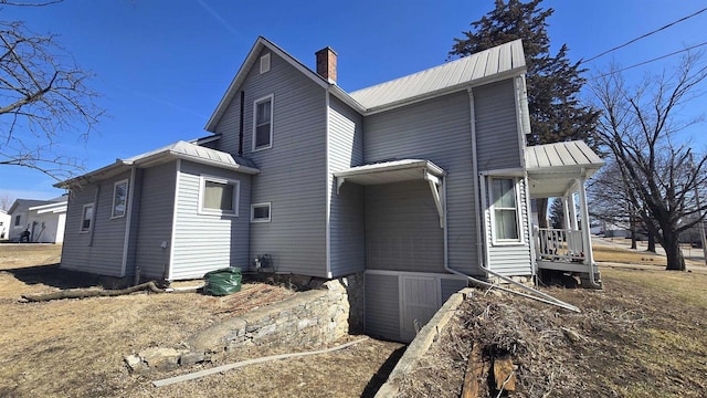 view of property exterior with a chimney and metal roof