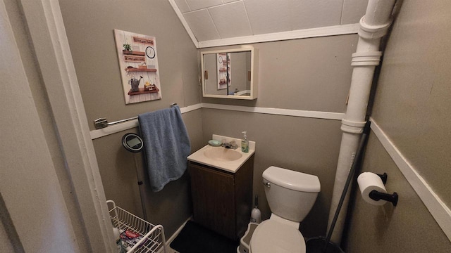 half bath featuring toilet, vanity, and vaulted ceiling