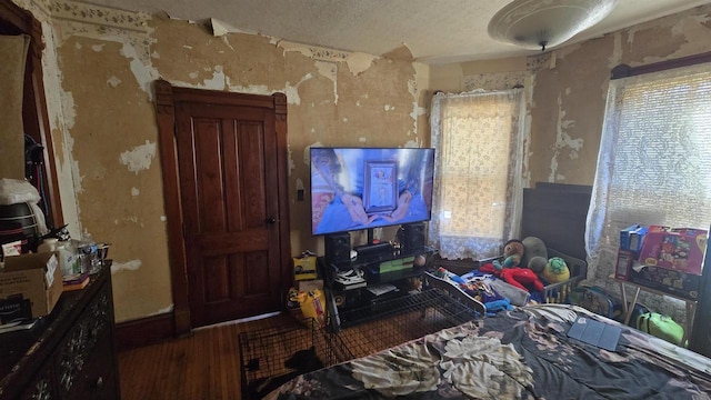 bedroom with multiple windows, wood finished floors, and a textured ceiling