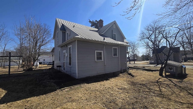 view of property exterior with a chimney, a standing seam roof, and metal roof