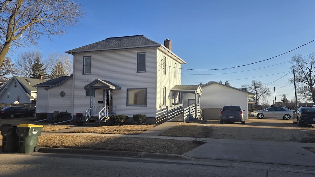 view of front of home featuring a chimney and a shingled roof