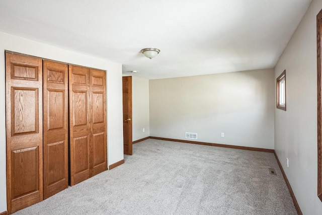 unfurnished bedroom featuring a closet, visible vents, baseboards, and carpet