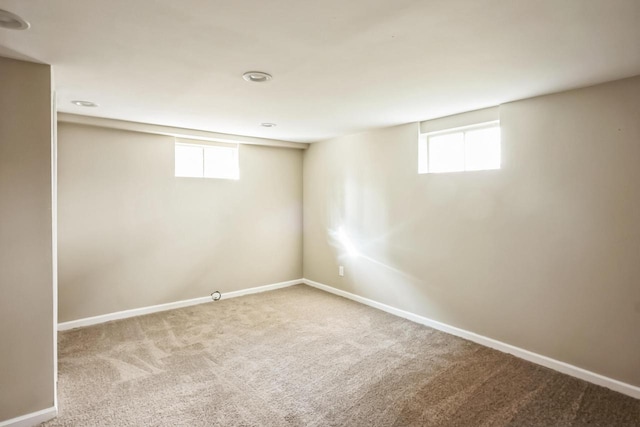 below grade area with plenty of natural light, baseboards, and carpet floors