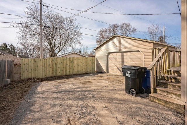 view of yard with an outbuilding, driveway, a detached garage, fence, and stairway