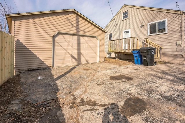 exterior space featuring a garage, an outdoor structure, driveway, and fence