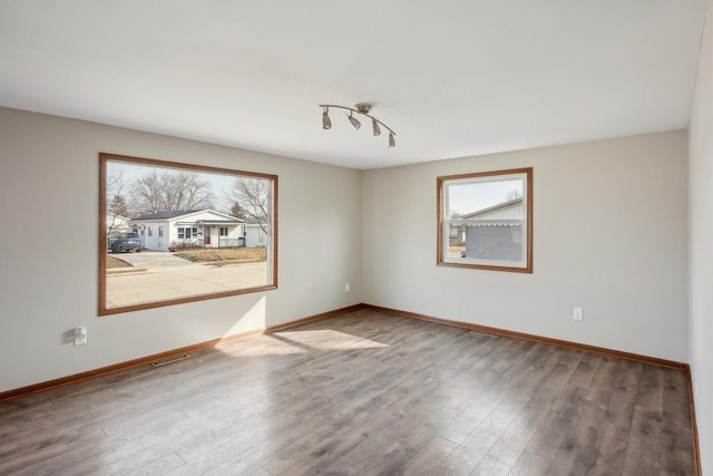 unfurnished room with baseboards and wood finished floors