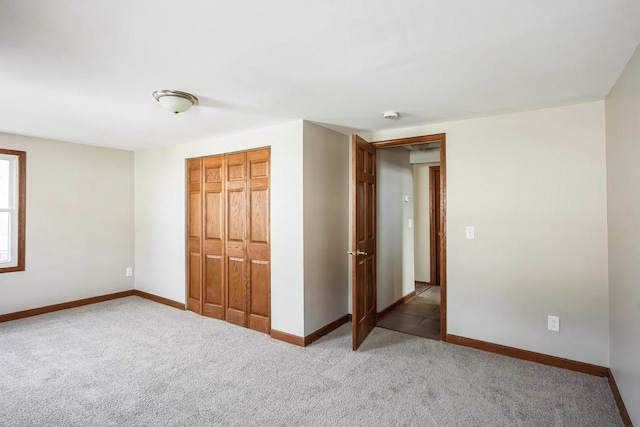 unfurnished bedroom featuring a closet, light colored carpet, and baseboards