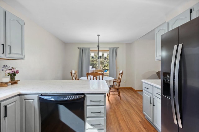 kitchen featuring a peninsula, light wood-style flooring, hanging light fixtures, dishwasher, and stainless steel fridge