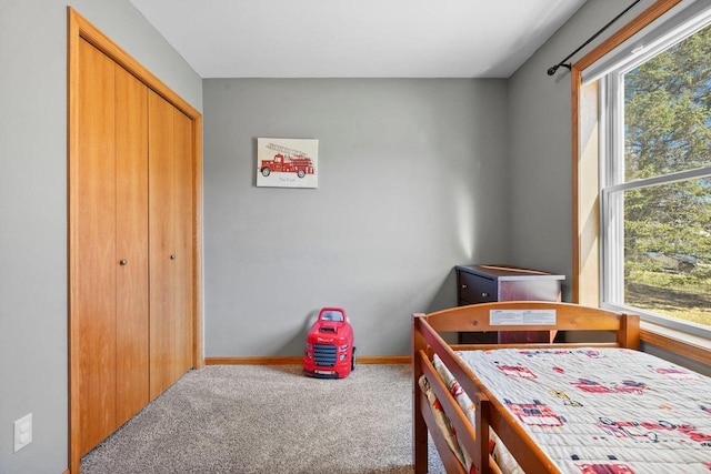 carpeted bedroom with a closet and baseboards