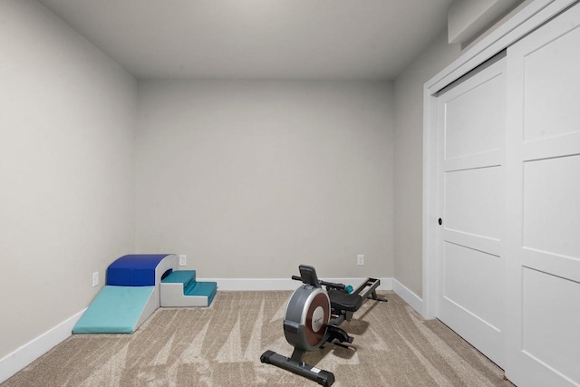 workout area featuring baseboards and carpet flooring