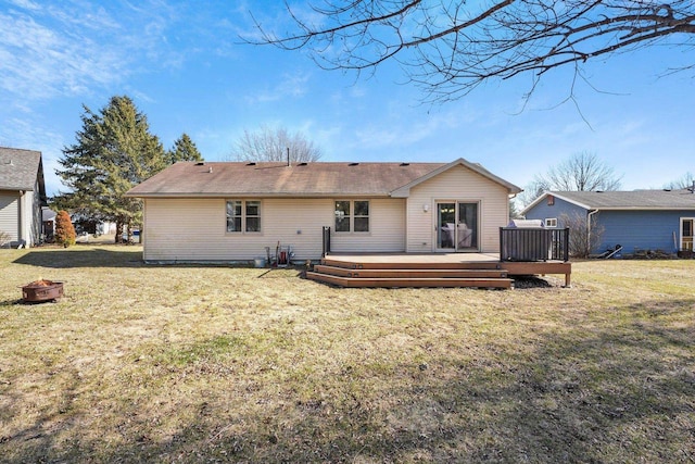 rear view of property with a yard, a fire pit, and a wooden deck