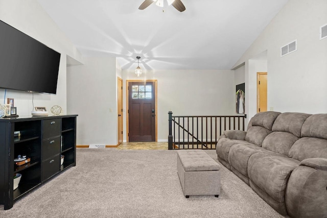 living room with a ceiling fan, visible vents, baseboards, vaulted ceiling, and light colored carpet