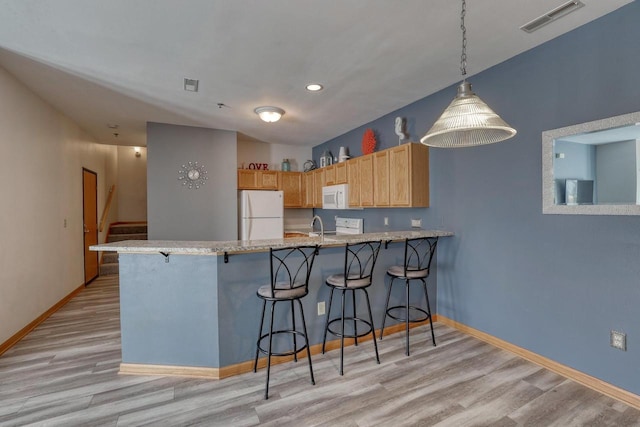 kitchen with visible vents, baseboards, light wood-style flooring, a peninsula, and white appliances