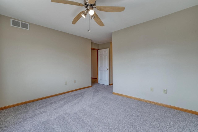 carpeted spare room featuring visible vents, baseboards, and ceiling fan