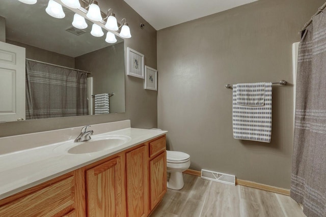 full bath featuring vanity, toilet, wood finished floors, and visible vents