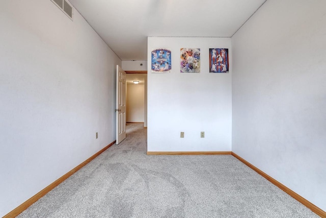 carpeted spare room with visible vents and baseboards