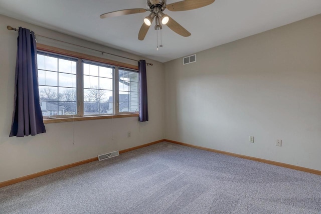 carpeted empty room with visible vents, baseboards, and ceiling fan