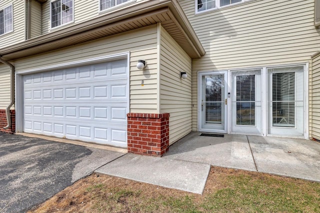 view of exterior entry featuring an attached garage and driveway