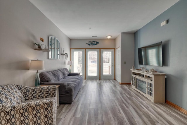 living area featuring baseboards and light wood finished floors