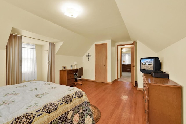 bedroom featuring lofted ceiling, light wood-style flooring, and baseboards