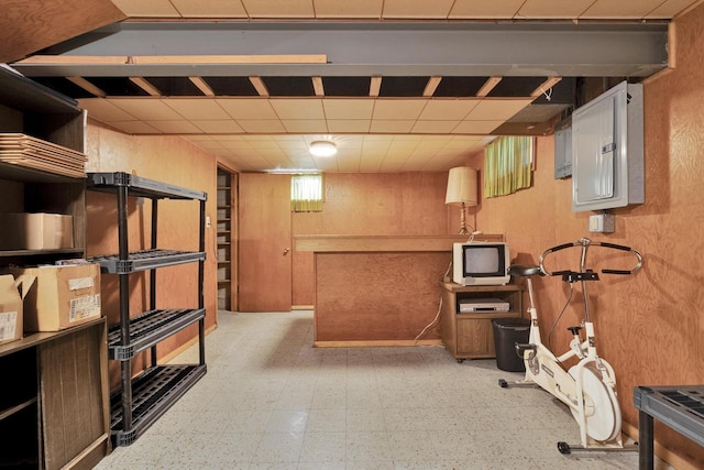 finished basement featuring electric panel, a drop ceiling, and light floors