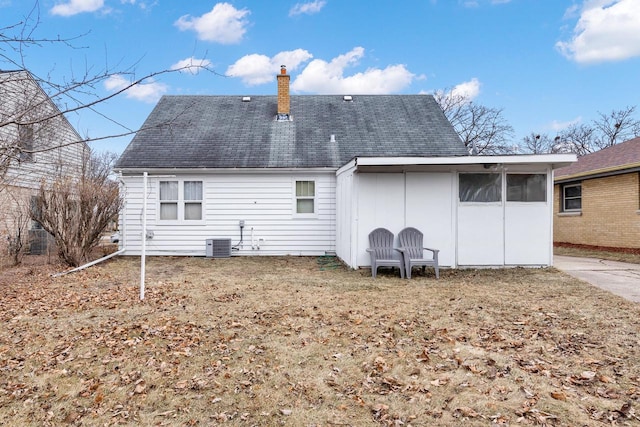 rear view of property featuring central AC unit and a chimney