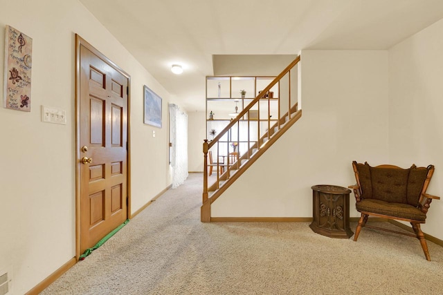 foyer entrance featuring stairway, baseboards, and carpet floors