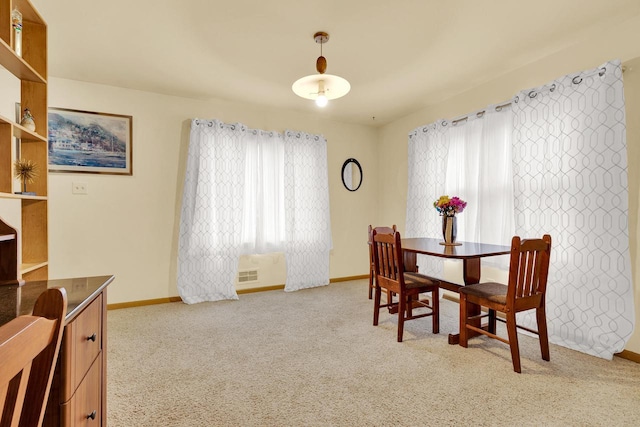 carpeted dining area with baseboards, visible vents, and a wealth of natural light