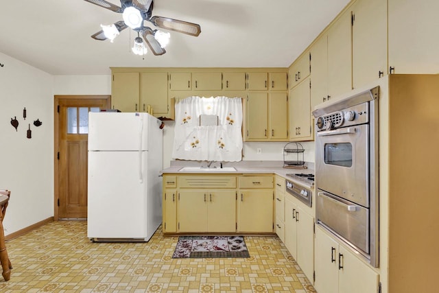 kitchen featuring a warming drawer, freestanding refrigerator, a sink, oven, and cream cabinets