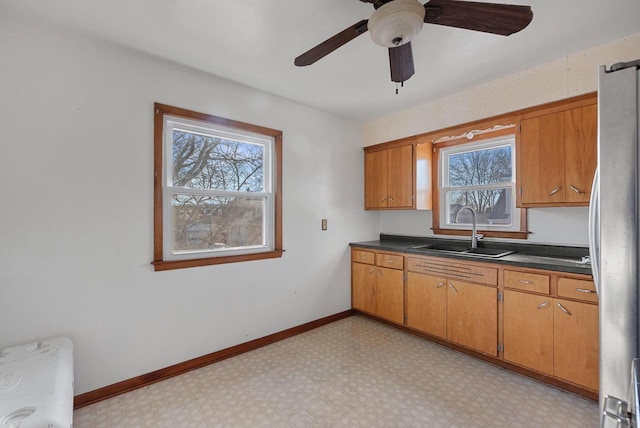 kitchen featuring a sink, plenty of natural light, light floors, and freestanding refrigerator