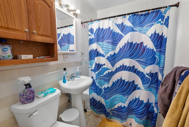 bathroom featuring curtained shower, toilet, tile walls, and a sink