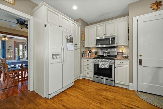 kitchen featuring wood finished floors, a ceiling fan, recessed lighting, white cabinets, and appliances with stainless steel finishes